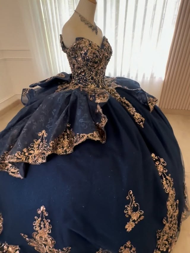 Vestido de quinceañera azul marino con aplicaciones doradas